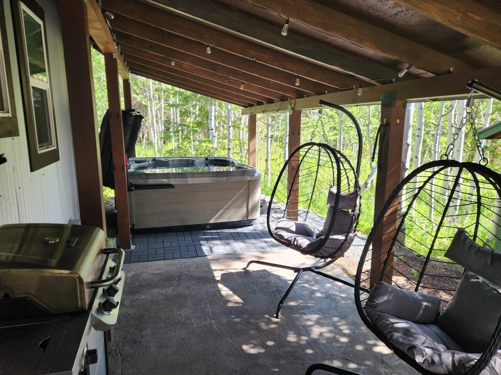 Hot tub on the covered patio with hanging chairs and aspen views