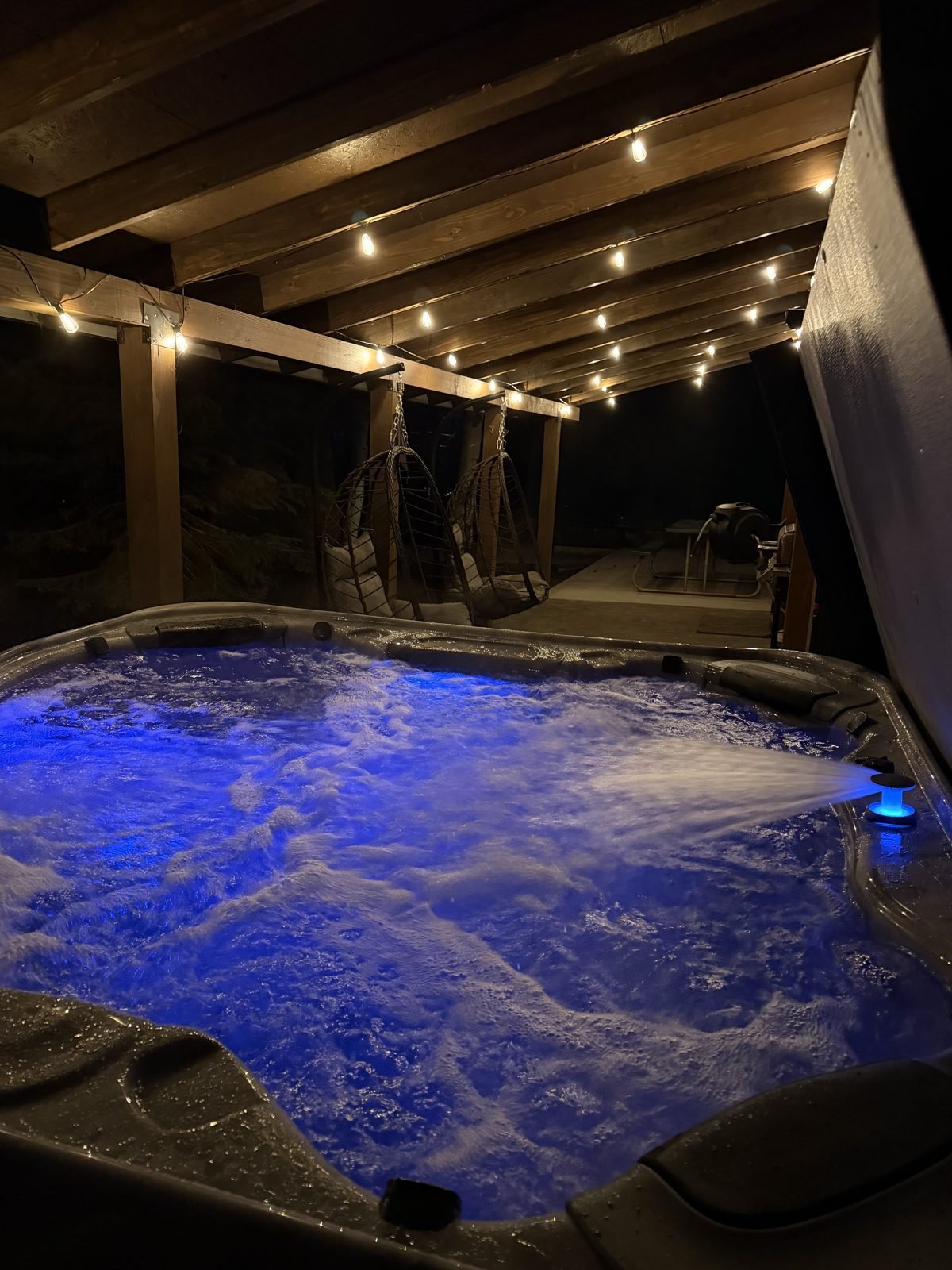 Private hot tub glowing at night under the covered patio
